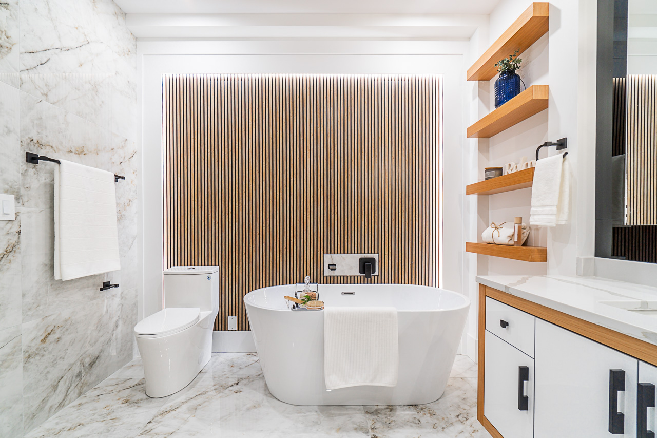 Freestanding bathtub framed by stone and vertical wood details