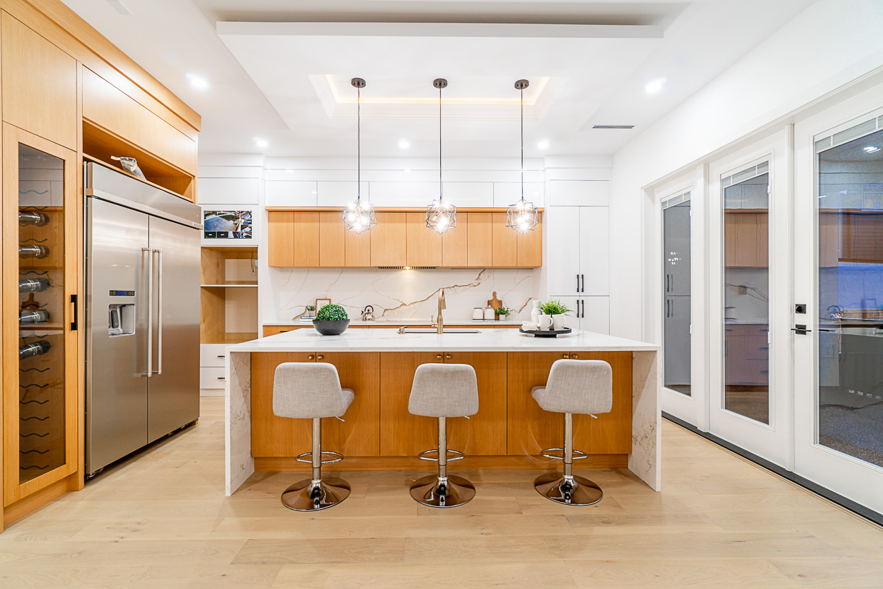 Custom kitchen with natural wood cabinetry, stone island and pendant lighting
