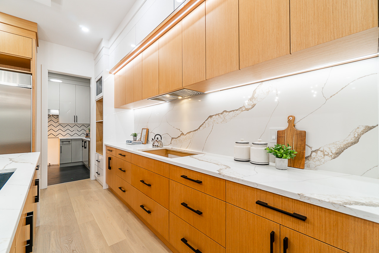 Warm wood cabinetry and a veined stone kitchen backsplash