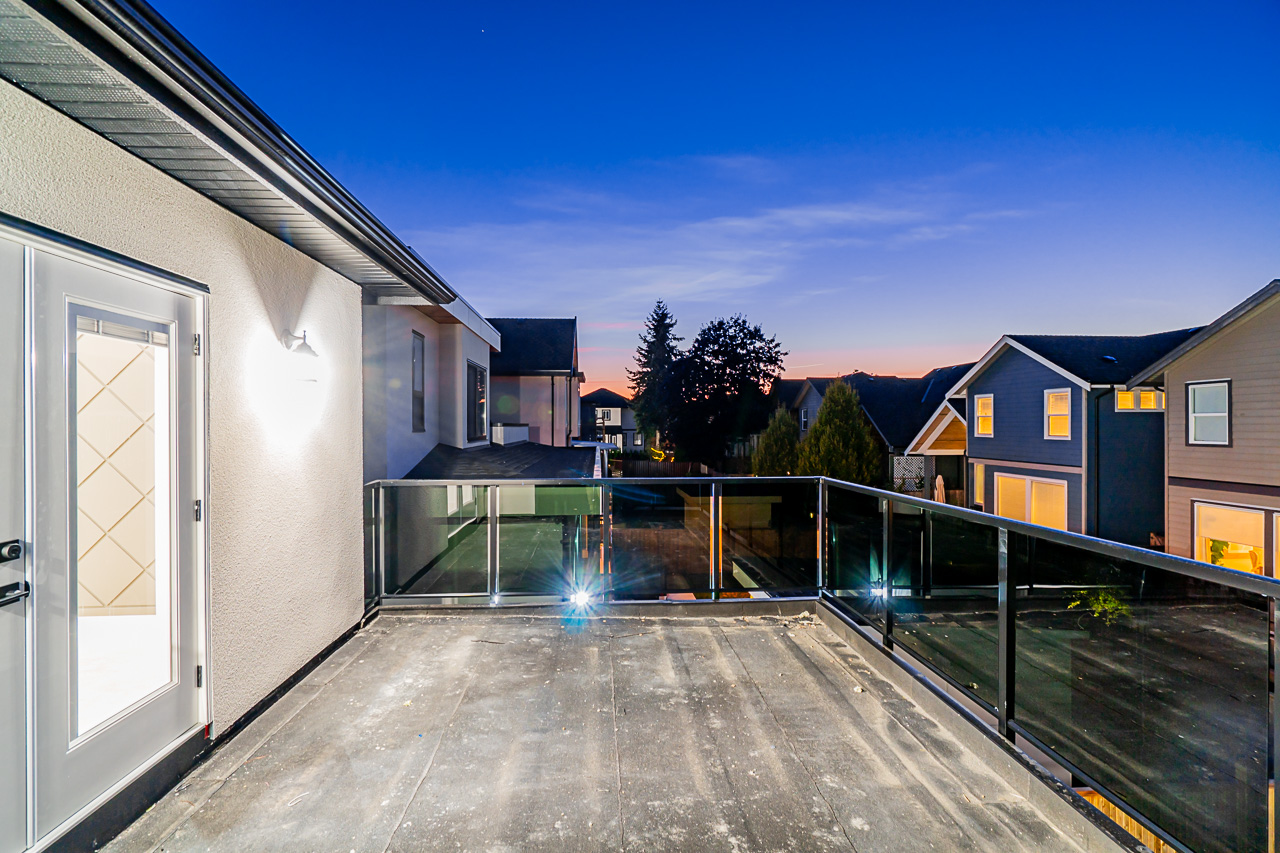 Glass-railed terrace looking over the neighbourhood at dusk